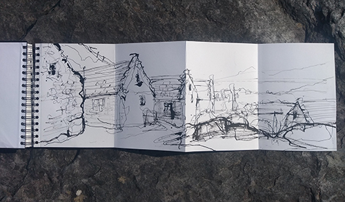 A drqwing in a concertina sketchbook of stone buildings